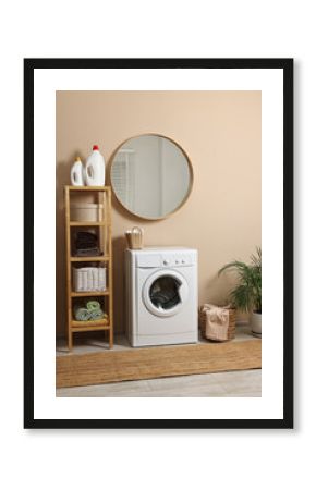 Stylish laundry room interior with washing machine, furniture and houseplant