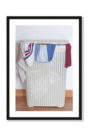 A dirty laundry hamper with some clothes coming out from the cover.