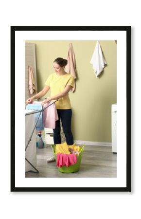 Young woman hanging laundry on clothes dryer after washing