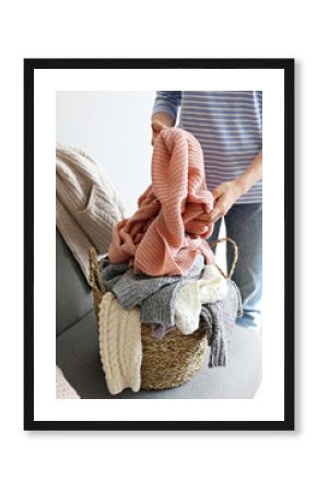 Categorizing winter laundry concept. A messy pile of kniwear lying on grey textile sofa. Bunch of unfolded sweaters prepeared for sorting. Close up copy space, background.