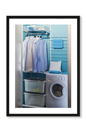 piles of clean clothes in laundry room. Laundry closet. Washing room, modern design with a laundry machine with hangers for clothes, an iron, shelves and a washing machine