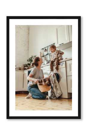 Happy family mother housewife and child   in laundry with washing machine .