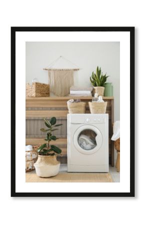 Modern washing machine and plants in laundry room interior