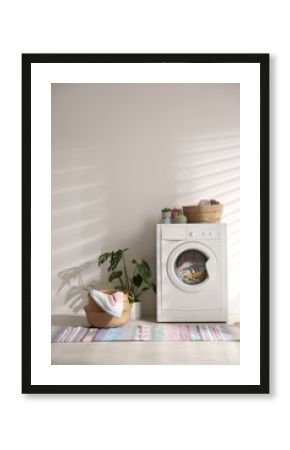 Modern washing machine and wicker basket with laundry near white wall. Interior design