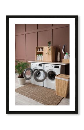 Interior of laundry room with washing machines, basket and plants