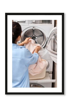 housewife put laundry in automatic washing machine with open door