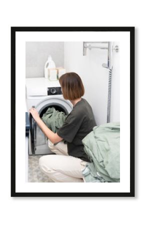 Housewife putting laundry in the washing machine 