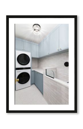 A laundry room with blue cabinets, white washer and dryer, circular tile flooring, subway tile backsplash, and a chandelier hanging above.