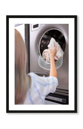 Female putting dirty laundry into washing machine indoors, closeup. rear view