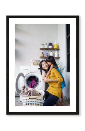 Beautiful young asian woman and child girl little helper are doing laundry at home.