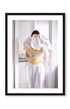 Young girl carrying a laundry basket filled with white bath towels 