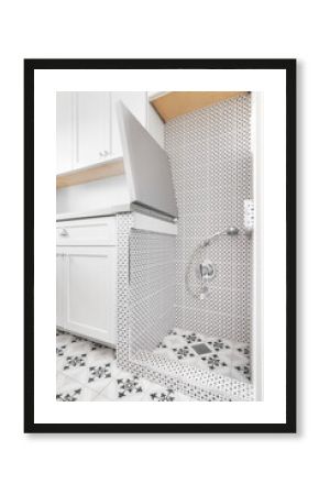 A pet wash station in a renovated laundry room with white cabinets, patterned tiles, and a chrome faucet.