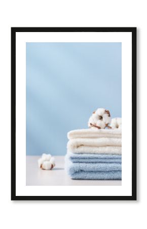 Stack of organic cotton terry towels on blue background with copy space. Delicate textiles, bath accessories