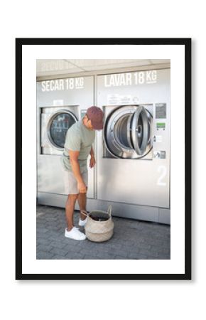 young man doing laundry in a city laundry