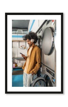 an with Headphones Using Smartphone at Laundromat
