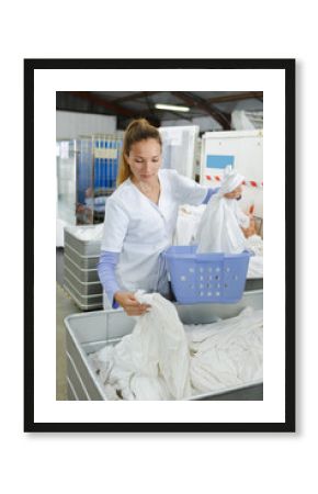 young female employee putting clothes in washing machine