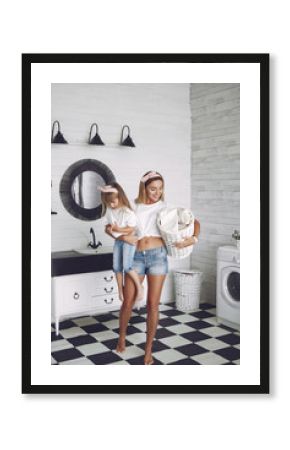 Family in a bathroom. Mother and daughter near wash mashine. Girl in a white t-shirt.