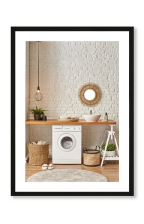 Washing machine in the laundry room, wooden table and shelf style, sink lamp mirror and wicker basket decor object.