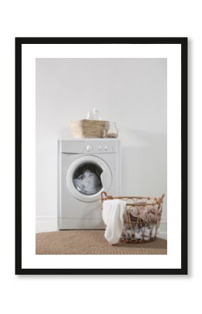 Modern washing machine and laundry baskets near white wall indoors. Bathroom interior