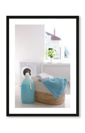 Wicker basket with towels and detergent on white table indoors. Space for text