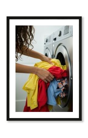 Hand putting clothes into washing machine for laundry