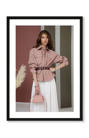 High fashion photo of a beautiful elegant young asian woman in pretty rosy brown shirt, belt, necklace, bracelets, white cream long skirt. Green striped Corrugated Wall, dry branches.