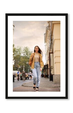 Young woman with backpack walking on city street