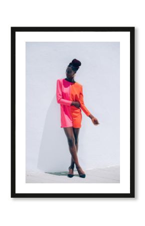 Exotic portrait of a beautiful and attractive black model woman wearing a red and pink dress with a fashion makeup posing on white background. Exotic fashion concept