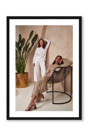 Two beautiful sexy brunette woman friends face cosmetic makeup tanned skin wear fashion clothes style beige white knitted suit sandals accessory interior furniture armchair journey summer palm boho.