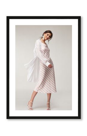 Sexy fashion model beautiful woman pretty face makeup, tanned skin wear summer collection clothes style for romantic date walk trendy light silk in white pink stripes long dress white shirt earrings.