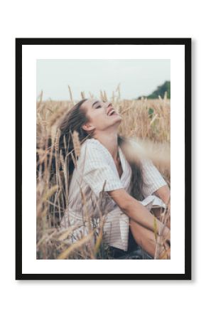  portrait of a girl of model appearance in wheat, a girl sits in a wheat field and smiles