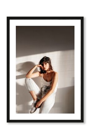 Portrait of a serious girl sitting on a column with a warm natural light on the side.