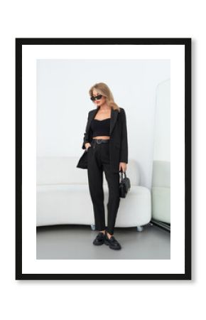 Elegant woman posing in stylish black outfit at modern fashion studio setting