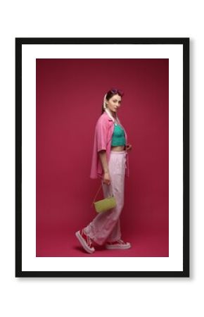 Fashionable full-length portrait of beautiful woman in stylish outfit on dark red background