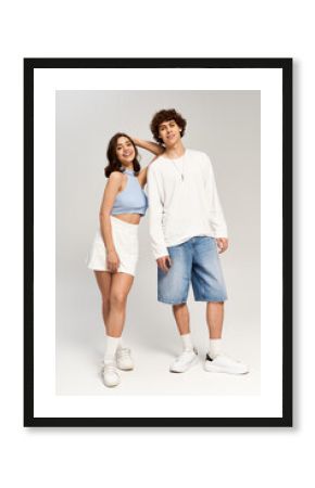 Young couple sharing playful moments in stylish outfits against a neutral backdrop