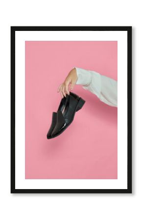 Mulher segurando sapatos em fundo rosa