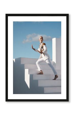 Unusual I take that as a compliment. Shot of a young model wearing stylish white clothes while walking up stairs against a sky background.