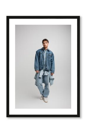 full length of young man in denim outfit posing and looking at camera on grey.