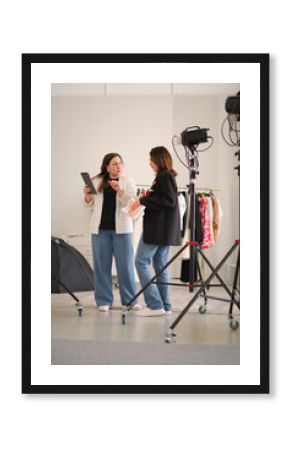 professional studio, two bloggers converse about their upcoming content, utilizing a tablet and fashion magazine for reference. This photo highlights the behind-the-scenes work in digital content