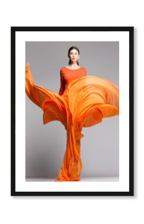 beautiful woman in long orange dress posing in the studio