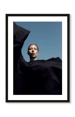 Portrait of a woman in black clothes posing against blue sky