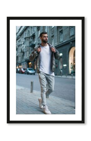 Handsome and casual. Full length of handsome young man adjusting his jacket while standing outdoors