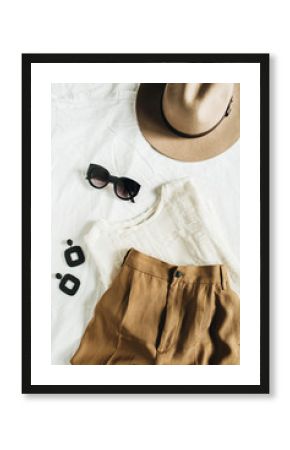 Fashion pastel composition with female clothes and accessories. Beige trousers, blouse, hat, sunglasses, earrings on white blanket. Flat lay, top view.