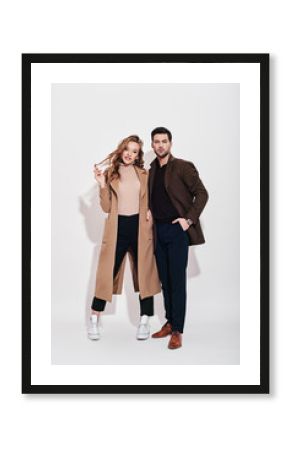 Looking perfect together. Attractive and well-dressed couple posing in studio. Isolated over grey background.