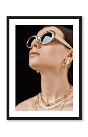 young attractive naked woman in sunglasses and golden jewelry isolated on black