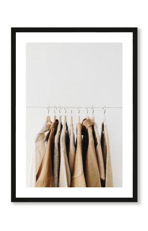 A hanger of warm beautiful feminine beige sweaters or pullovers. Autumn, fall, winter, fashion concept. Empty space, mock up. minimal background.