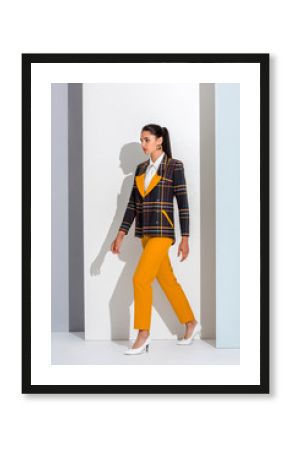 stylish girl in checkered formal wear walking on white and grey