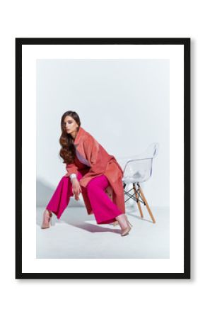 High fashion portrait of young elegant woman. Coral coat, magenta pants, white blouse.