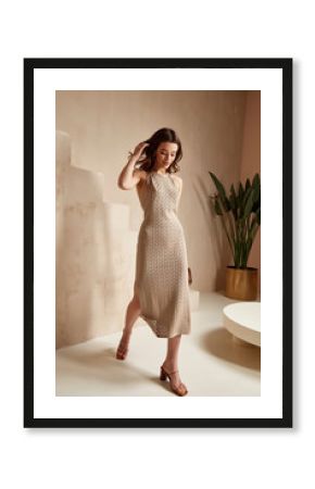 Sexy beautiful woman brunette tanned skin makeup cosmetic fashion clothes summer collection beige cotton dress accessory bag style summer journey walk date beach wear interior stairs leaves flowerpot.