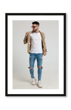 cool young fashion guy looking to side and fixing jacket